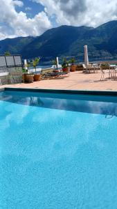 a large blue swimming pool with tables and chairs at Sollevante Ascona in Ascona