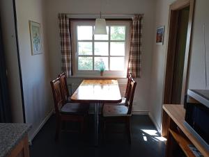 a dining room table with chairs and a window at Ferienhaus "Op'n Barg" in Holzbunge