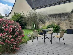 a patio with a table and chairs and flowers at Le coin de mire in Carentan
