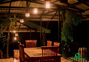 eine Terrasse mit einem Tisch, Stühlen und Lampen in der Unterkunft Nature Springs Belihul oya in Balangoda