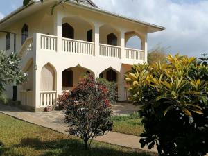 ein großes weißes Haus mit einem Garten davor in der Unterkunft Swahili Oasis in Diani Beach