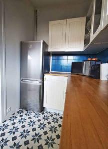 a kitchen with a refrigerator and a wooden floor at Bel Appartement 10mn PARIS in Argenteuil