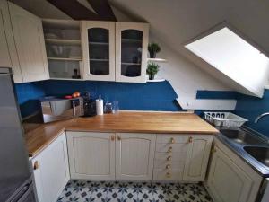 a kitchen with white cabinets and a wooden counter top at Bel Appartement 10mn PARIS in Argenteuil