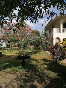 einen Hof mit blühenden Bäumen und einem Haus in der Unterkunft Swahili Oasis in Diani Beach