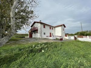 una casa blanca con un campo de hierba delante de ella en Eiherabidia, en Orsanco