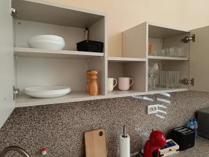 Una encimera de cocina con gabinetes blancos con platos encima. en Апартамент Арките, en Balchik 25 fotos más