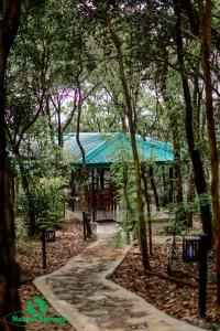 a path through a forest with a building with a green roof at Nature Springs Belihul oya in Balangoda