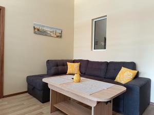 Una sala de estar con un sofá azul y una mesa. en Апартамент Арките, en Balchik