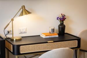 a desk with a lamp and a vase of flowers on it at Colosseum Boutique Apartment in Rome