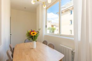 un vase de fleurs sur une table dans une chambre avec fenêtre dans l'établissement Colosseum Boutique Apartment, à Rome