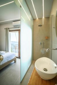 a bathroom with a sink and a shower and a bed at Omnia Deluxe Rooms in Parga