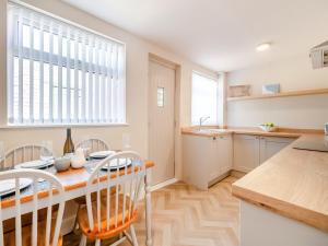 a kitchen with a wooden table and chairs and a dining room at Kew Cottage in Brotton