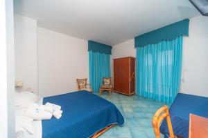 a bedroom with two beds and blue curtains at Hotel America in Marina di Camerota