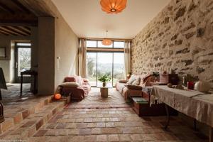 uma sala de estar com sofás e uma parede de pedra em Les Chaumes en Morvan 