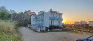 a large white house with a sunset in the background at KANALI HOLIDAYS APARTMENT 2 in Kanali