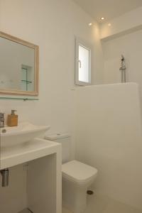 a bathroom with a sink and a toilet and a mirror at Amaris Mykonian Residence in Ornos