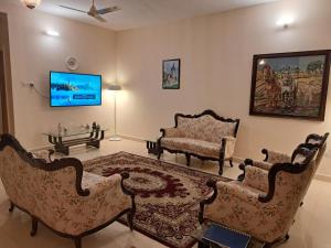 a living room with two chairs and a tv at BluSalzz Villas - The Pine Tree, Dalhousie - Himachal Pradesh in Dalhousie