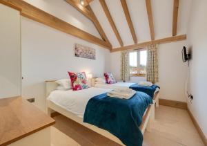two twin beds in a room with wooden ceilings at The Old Cowshed in Stone