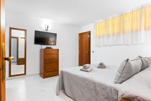 a bedroom with a bed and a flat screen tv at Neptuno Pool and beach private access in Puerto de Santiago