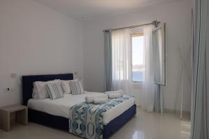 a white bedroom with a large bed and a window at Amaris Mykonian Residence in Ornos