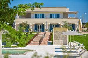 een gebouw met een zwembad, stoelen en een parasol bij Terra Home Resort in Spongano