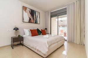 ein weißes Schlafzimmer mit einem Bett mit orangefarbenen und grünen Kissen in der Unterkunft Luxury and Large 2 Bedroom - Rav Kuk Residence in Jerusalem