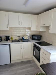 a kitchen with white cabinets and a sink and a microwave at O'Connors Bar Restaurant and Guesthouse in Dromore