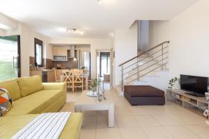 a living room with a yellow couch and a kitchen at Villa Orelia in Hanioti