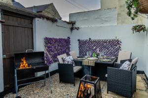 a patio with a table and chairs and a fireplace at Shorethwaite in Amble