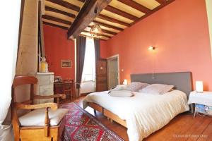 a bedroom with red walls and a bed and a chair at Manoir de Coulandon in Argentan