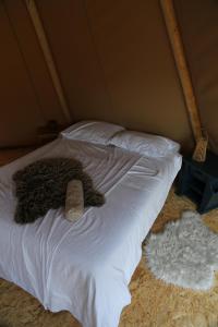 a bed with white sheets and a comforter at Tipi Texel in 't Horntje