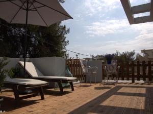 a patio with chairs and an umbrella on a deck at Pepi's room in Artemida