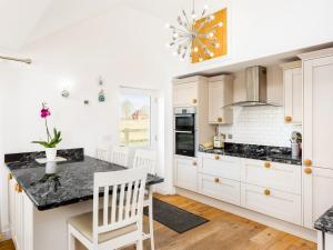 a kitchen with white cabinets and a black counter top at Pass the Keys Quality Rural 2 Bed Cottage Retreat in Warwick