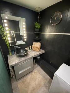 een badkamer met een wastafel en een klok aan de muur bij Studio cocooning - Terrasse - Jardin - Piscine in Menton