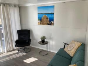 a living room with a green couch and a chair at Houseboot Cormorant, lake view in Biddinghuizen