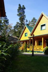 a large yellow house with a green roof at Zielone Domki in Pobierowo
