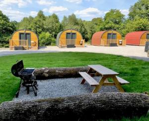 einem Picknicktisch und einer Bank vor einigen Zelten in der Unterkunft Forest Pod 4 Pet Friendly in Neath