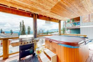 a large deck with a hot tub and a grill at Snow Leopard's Retreat in Big White