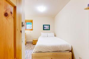 a bedroom with a white bed and a wooden door at Snow Leopard's Retreat in Big White