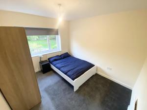 a small bedroom with a blue bed and a window at Tranquil Charming Stay in Atherton