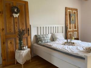 een slaapkamer met een wit bed en een houten deur bij Rancho „Czajone na pigwowcu” 