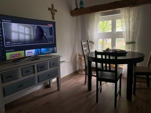 a dining room with a table and a television on a dresser at Rancho „Czajone na pigwowcu” in Lelkowo