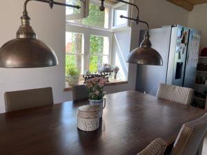 a kitchen with a wooden table with chairs and two lights at Rancho „Czajone na pigwowcu” in Lelkowo