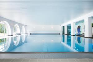 a swimming pool in a building with blue floors and windows at Hotel Schloss Montabaur in Montabaur