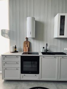 una cucina con armadi bianchi e un forno a piano cottura nero di Wind Shelter Svencele a Svencelė