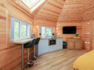 a log cabin kitchen with a desk and a tv at Honeybee Retreat in Pentney