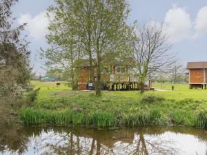 a house in a field with a pond in front at Honeybee Retreat in Pentney
