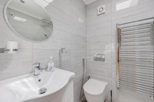 a bathroom with a sink and a toilet and a mirror at Entire Large Detached Bungalow The Star of Hatfield in Hatfield