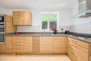 a kitchen with wooden cabinets and a sink at Entire Large Detached Bungalow The Star of Hatfield in Hatfield