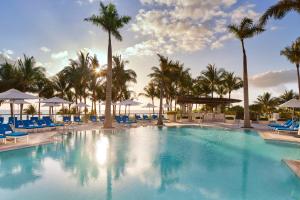 una gran piscina con sillas azules y palmeras en The St. Regis Bal Harbour Resort en Miami Beach